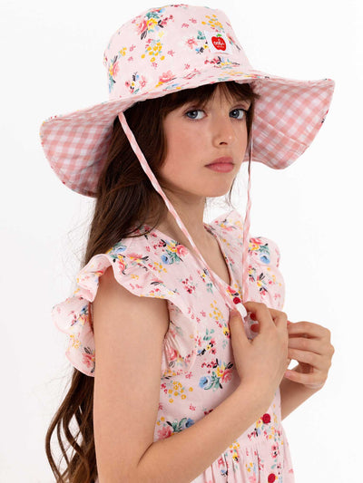 A young girl in a Vintage Pink Floral Chloe Hat from the brand Pink Flowers.
