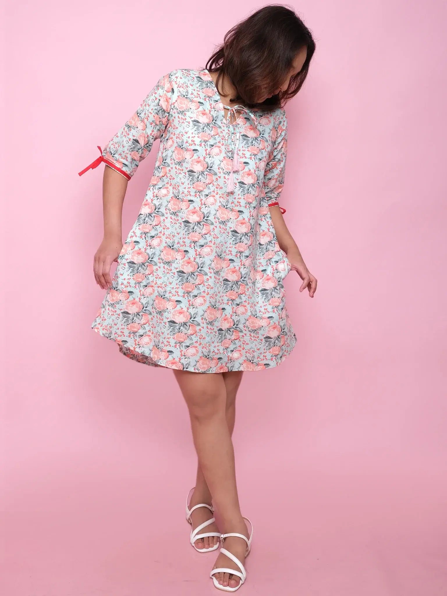 Woman wearing a floral dress against a pink background
