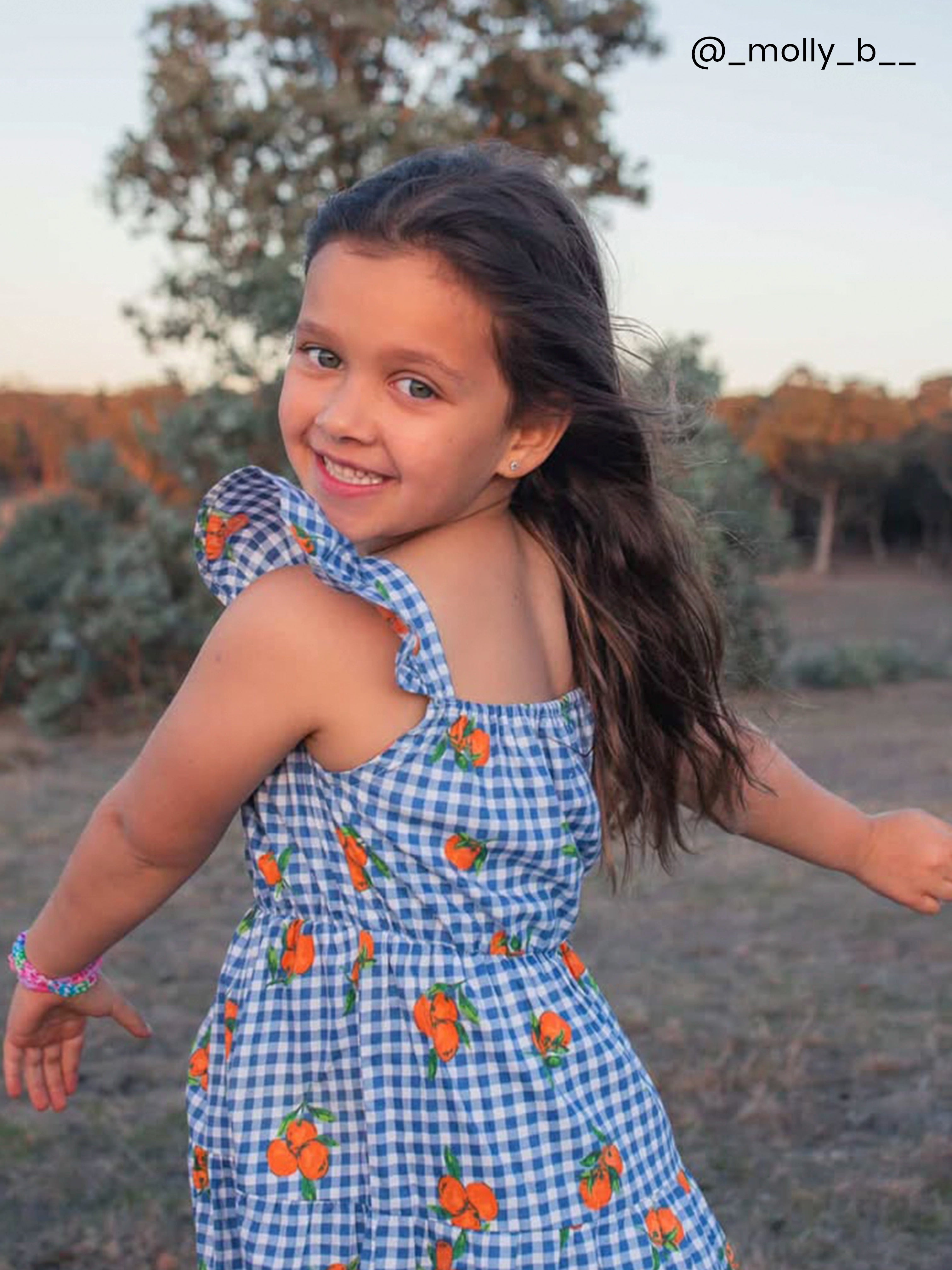 Girl in a gingham dress with oranges for summer