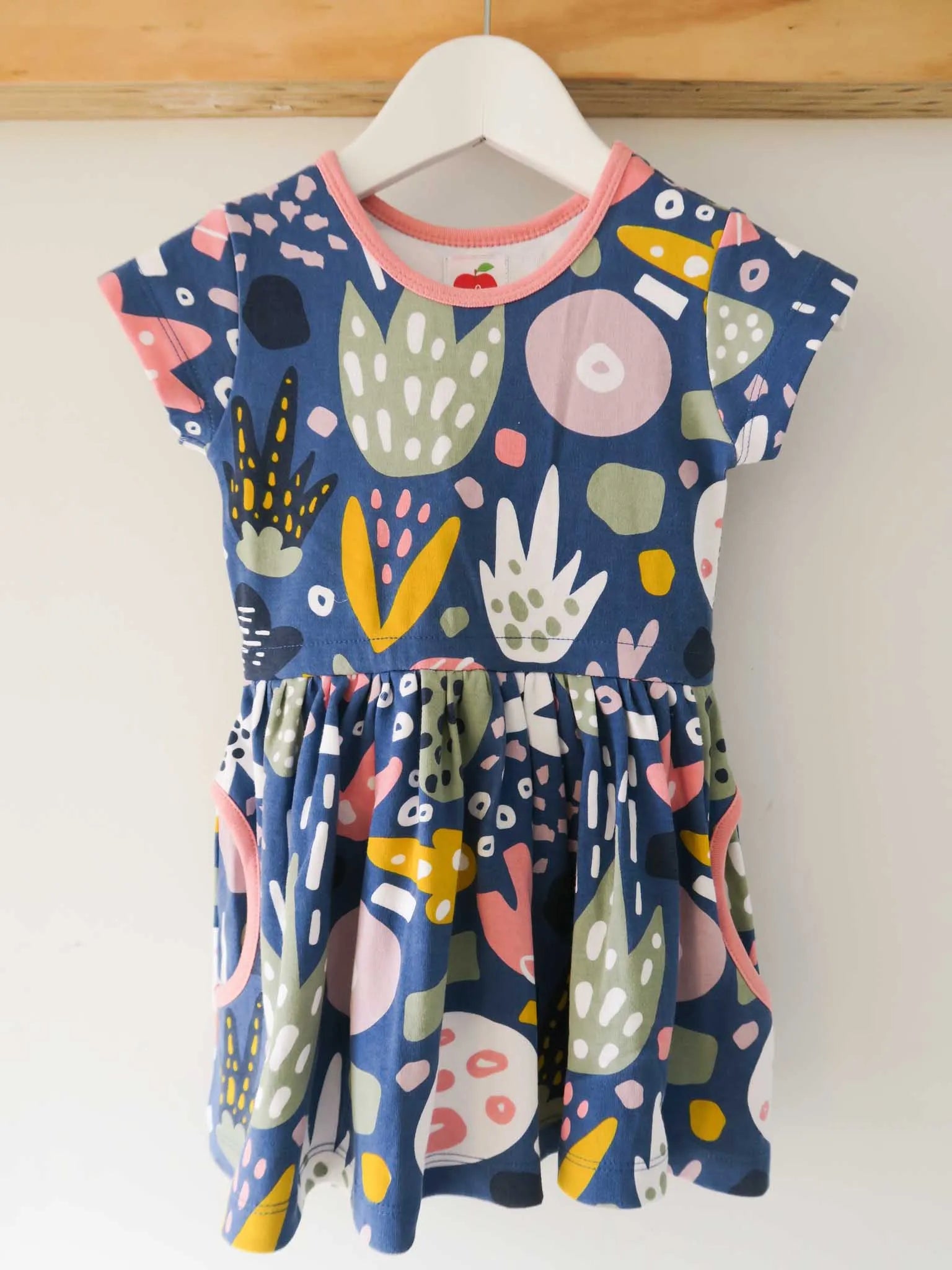 A navy blue abstract print design dress hanging from a white hanger
