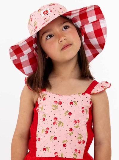 A little girl in a red and white gingham dress and hat.