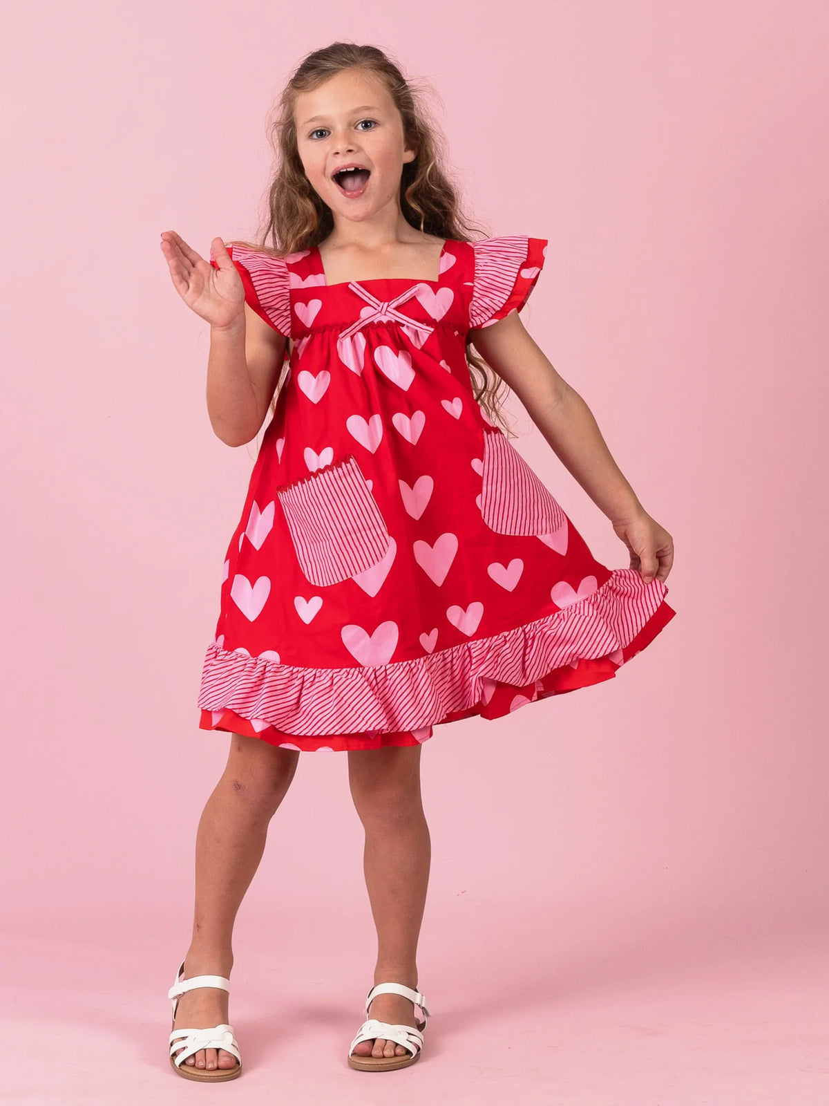 Girl holding the skirt of her Big Red Heart Holly dress