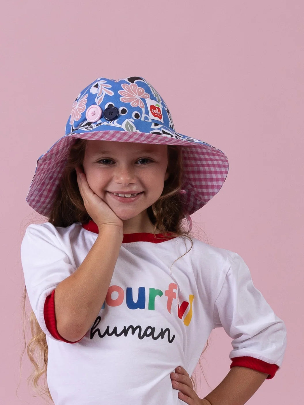 Girl smiling in the Blue/Pink Chloe ponytail hat, blue floral brim with pink gingham lining