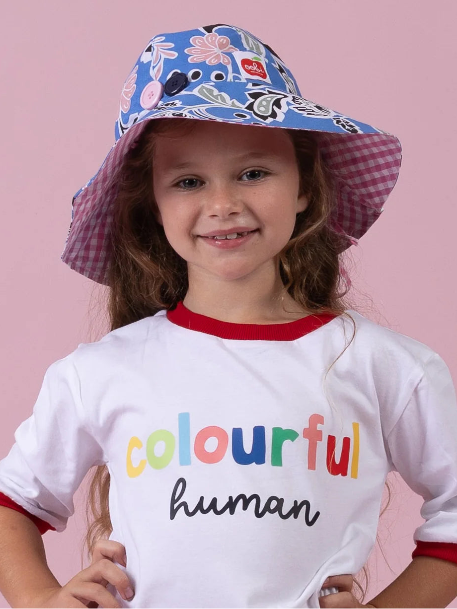 Girl smiling in the Blue/Pink Chloe ponytail hat, blue floral brim with pink gingham lining