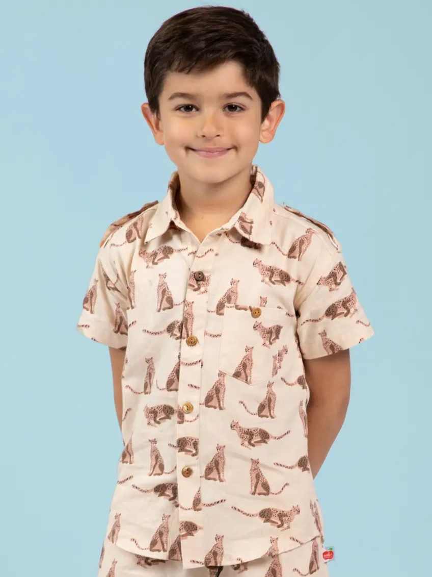 Child wearing a beige, leopard animal-patterned collared shirt with a blue background