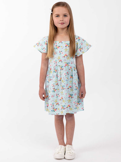 A little girl in an Amity Dress Vintage Blue Floral by Blue Floral standing on a white background.