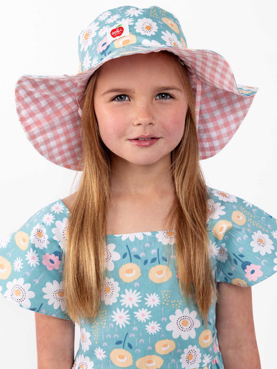A little girl wearing a Chloe Happy Daisy Hat with flowers on it.