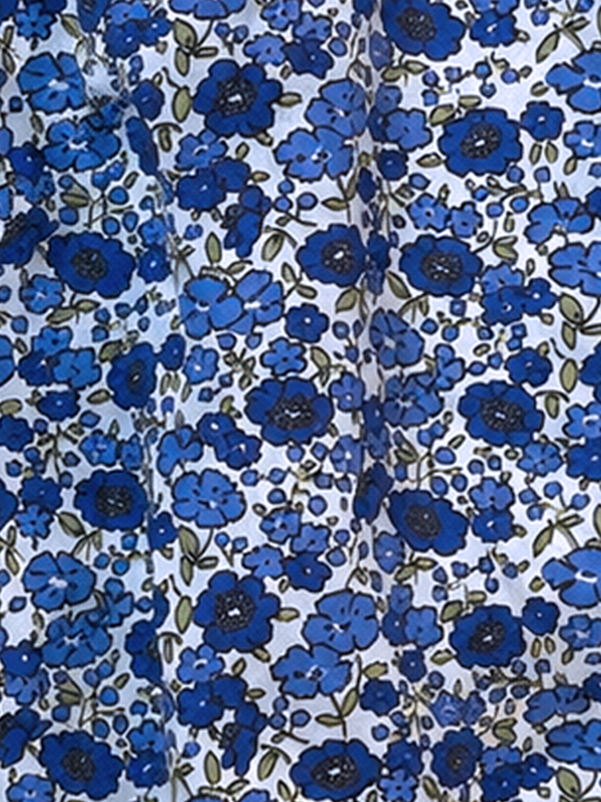 A close-up of a white fabric with an all-over blue floral print, featuring medium and dark blue flowers with olive green leaves.