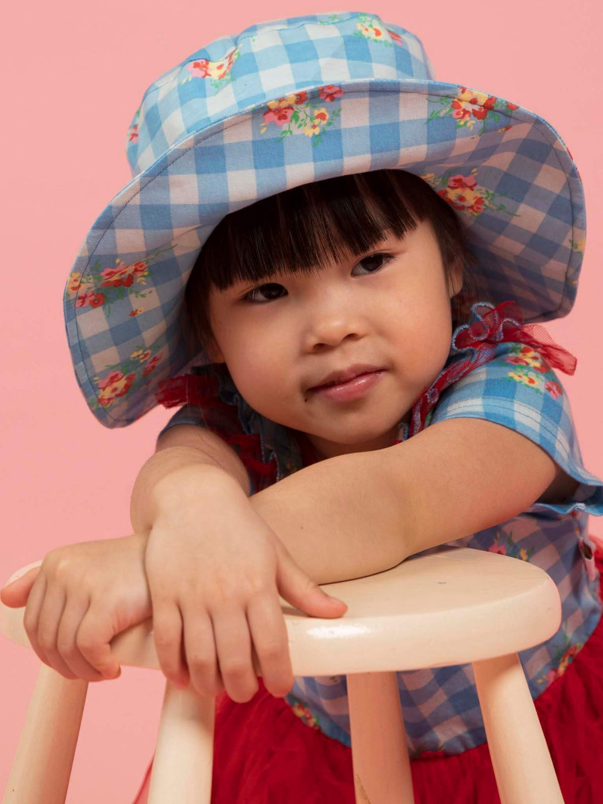 Girl in the Floral Gingham ponytail sun hat leaning on a stool