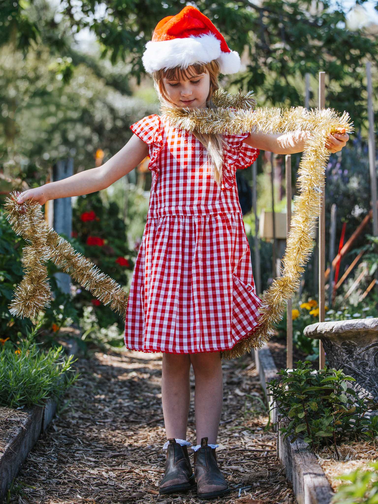 Girl and mum wearing Oobi Christmas dresses for family photos under the tree.