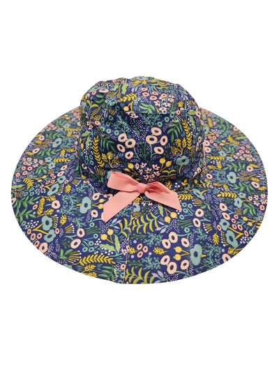 Patterned wide-brimmed Blue Lotus Chloe Hat with a ponytail hole and a pink bow.
