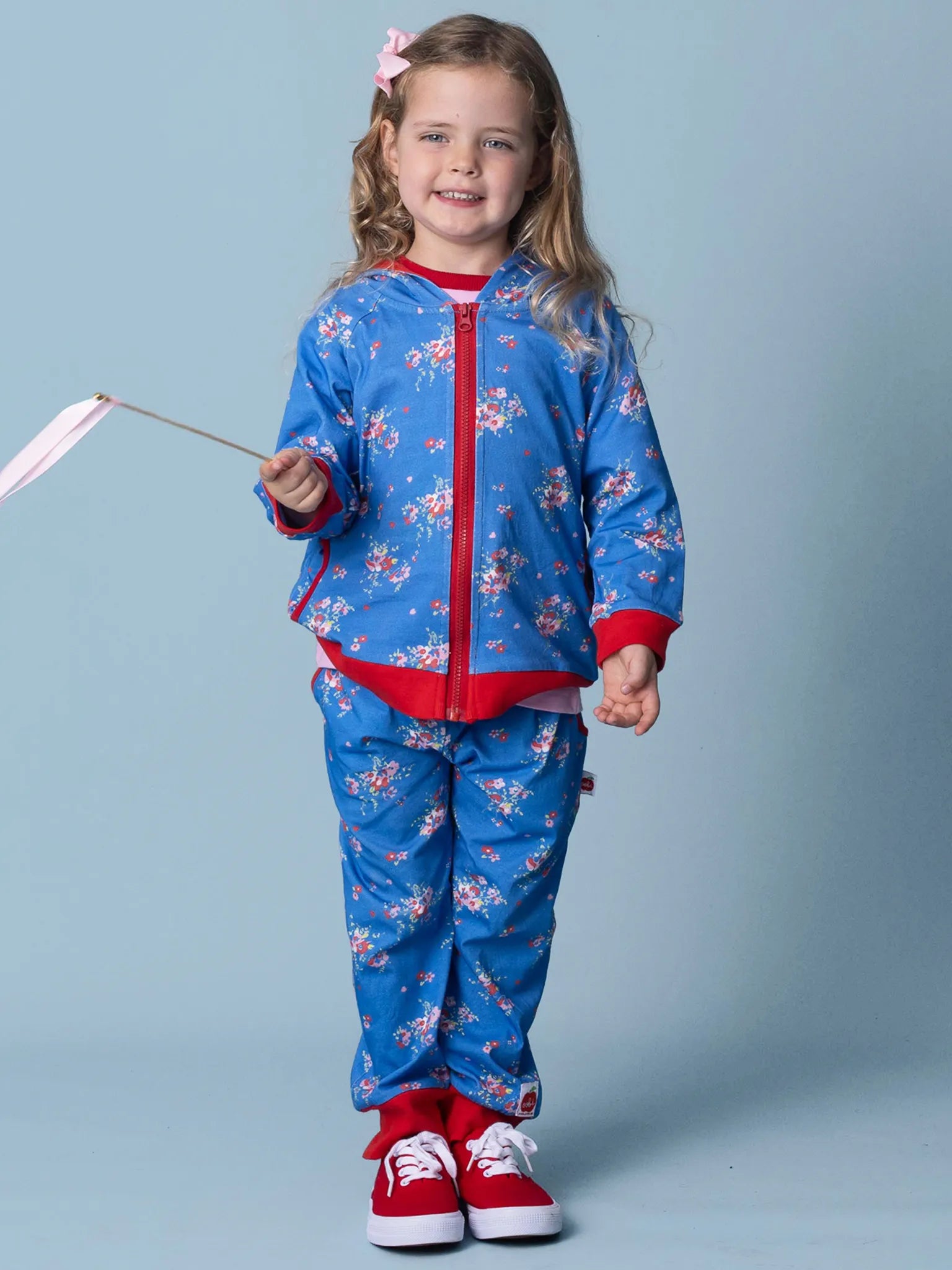 Child wearing a blue and red outfit with floral patterns on a light blue background