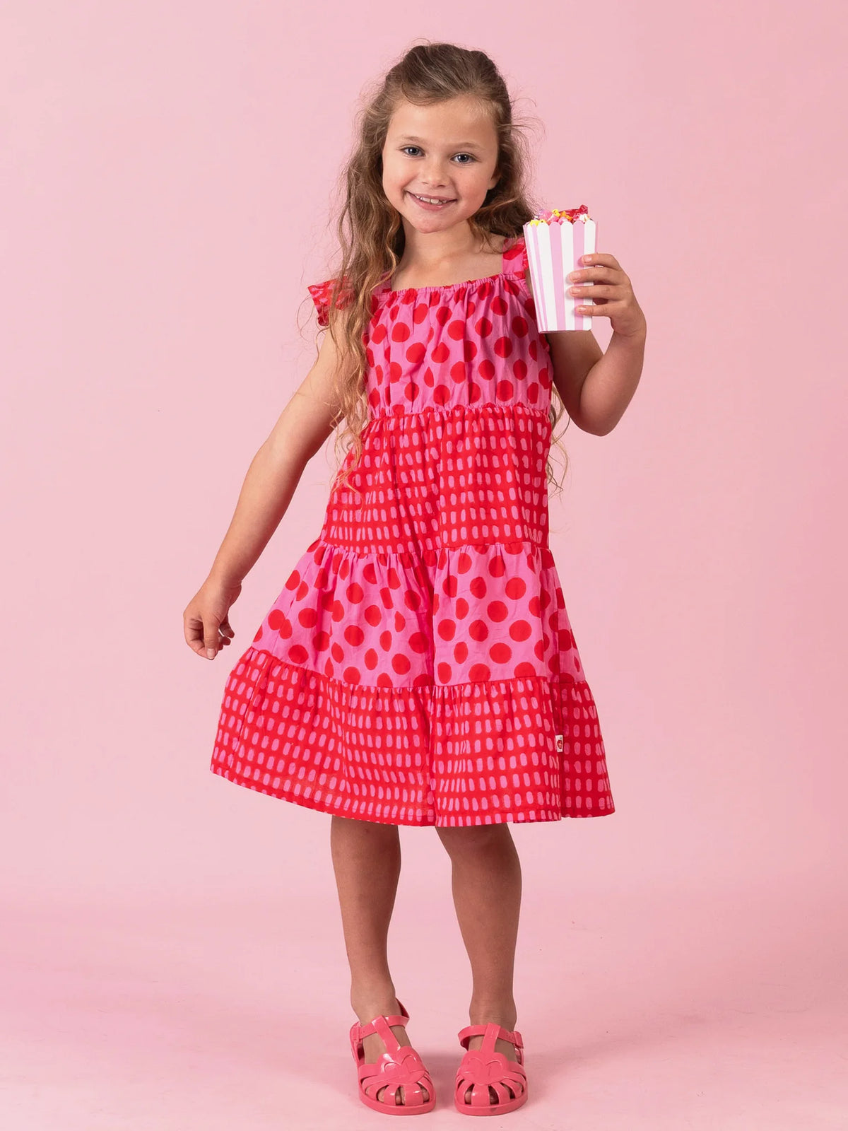 Girl in the Jaipur Block-Print Holiday dress with flutter sleeves holding popcorn