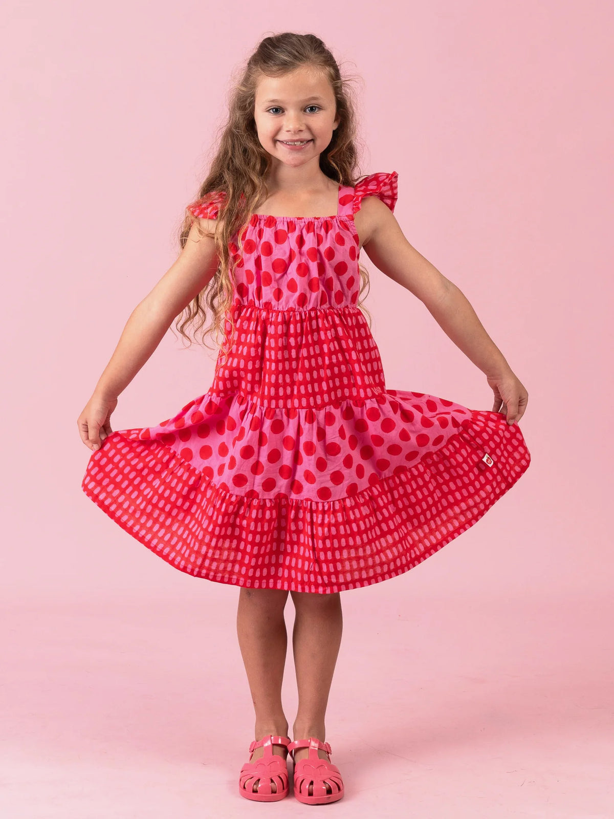 Girl holding out the tiered skirt of the Jaipur Block-Print Holiday dress