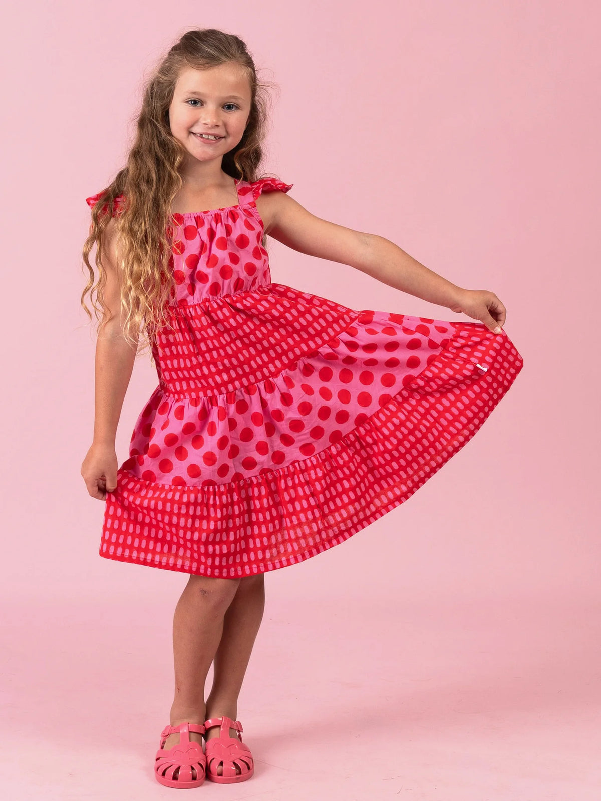 Girl showing the tiered skirt of the red and pink Jaipur Holiday dress