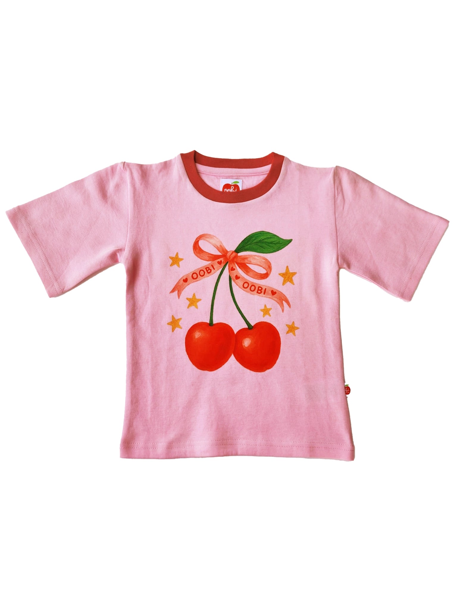 Essentials Pink Cherry Tee with Red Binding: Oversized heavyweight cotton tee in pink, featuring a red collar and a graphic with cherries, "Oobi Oobi" ribbon, green leaves, and yellow stars.