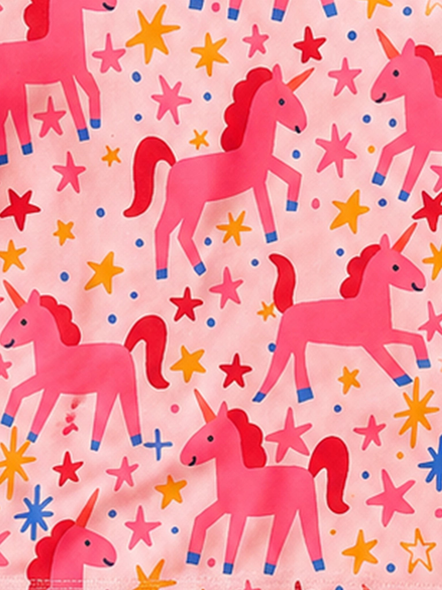 Pink fabric with a repeating pattern of pink unicorns, yellow and red stars, and small blue dots.