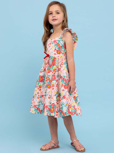 A little girl in a Cornflower Wild Meadow Maxi Dress standing on a blue background.
