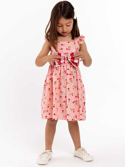 Retro Cherry's Mia, a little girl wearing a pink dress and white shoes, embraces vintage styling and exudes Cherry Ripe's 1950s style fun.