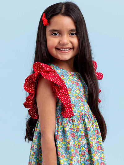 A little girl wearing a New Minifloral Molly Minifloral Dress with ruffled sleeves in a mini floral print.