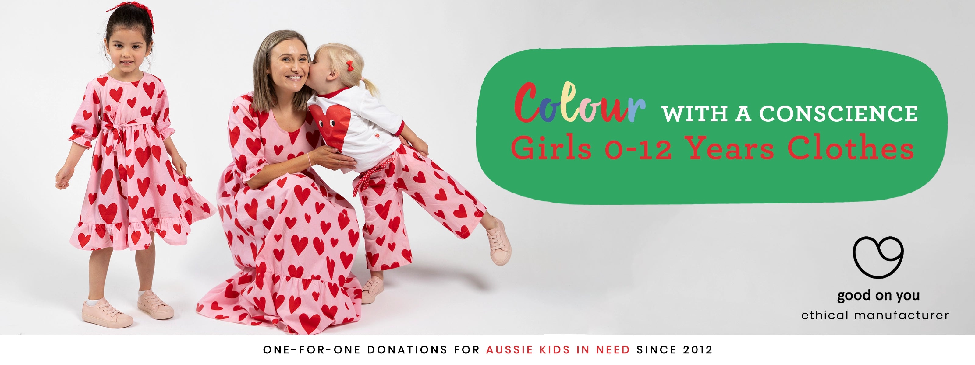 A mum and two children wearing matching red and white heart-patterned dresses and pants outfit for Christmas and special occasions