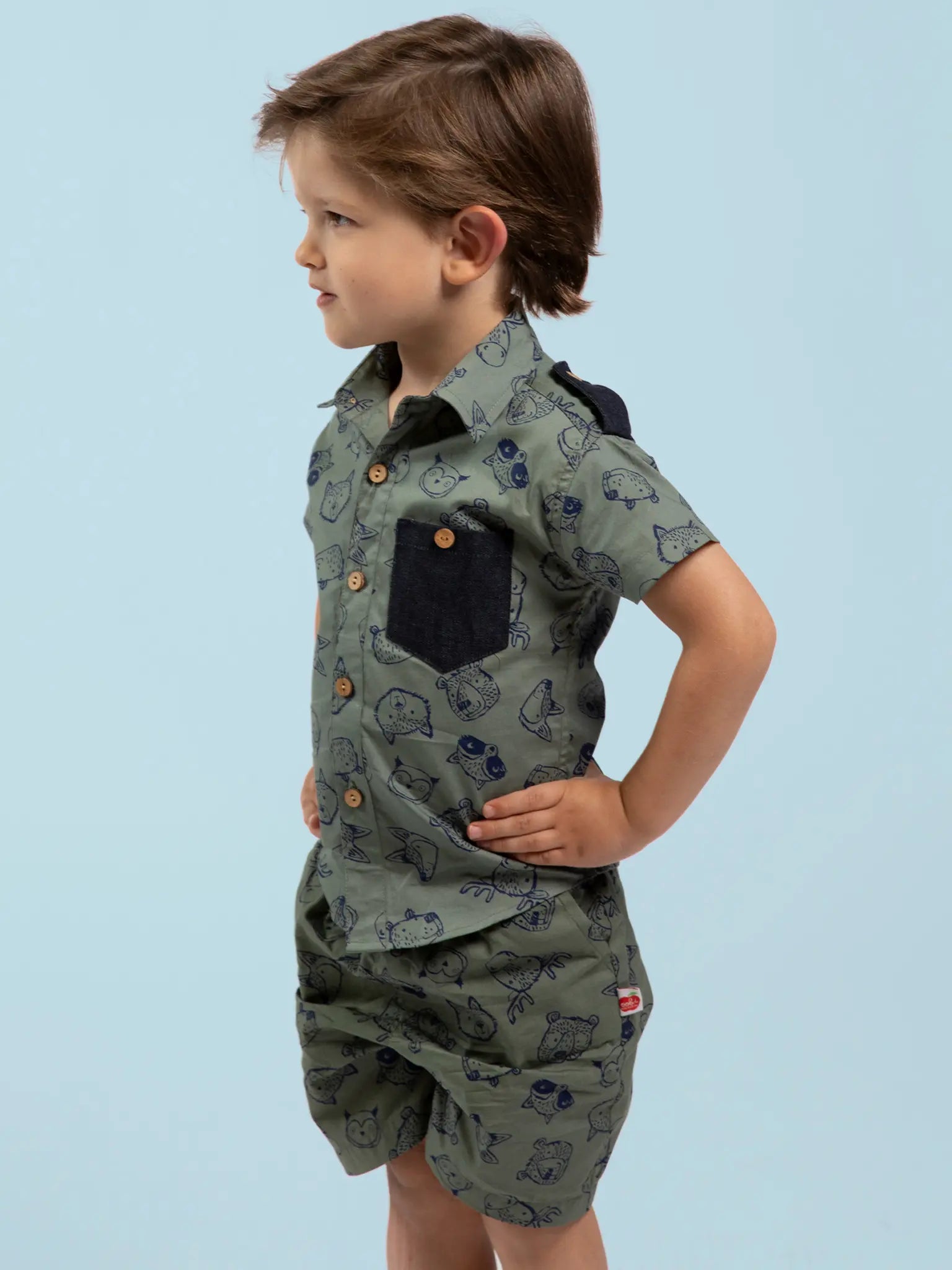 Child wearing a green patterned outfit on a light blue background