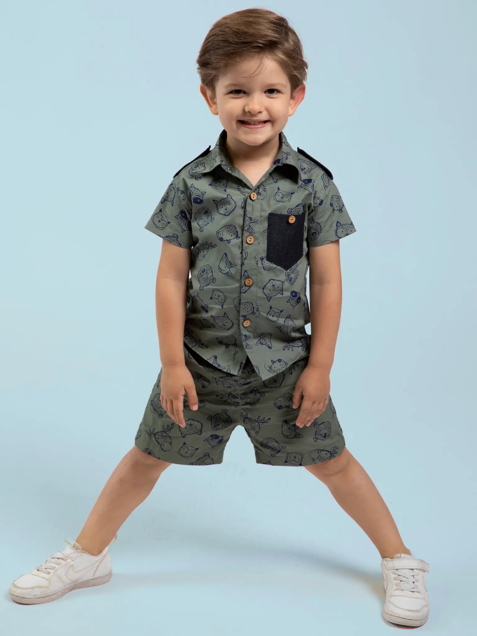 Child wearing an animal-patterned shirt and shorts set on a light blue background