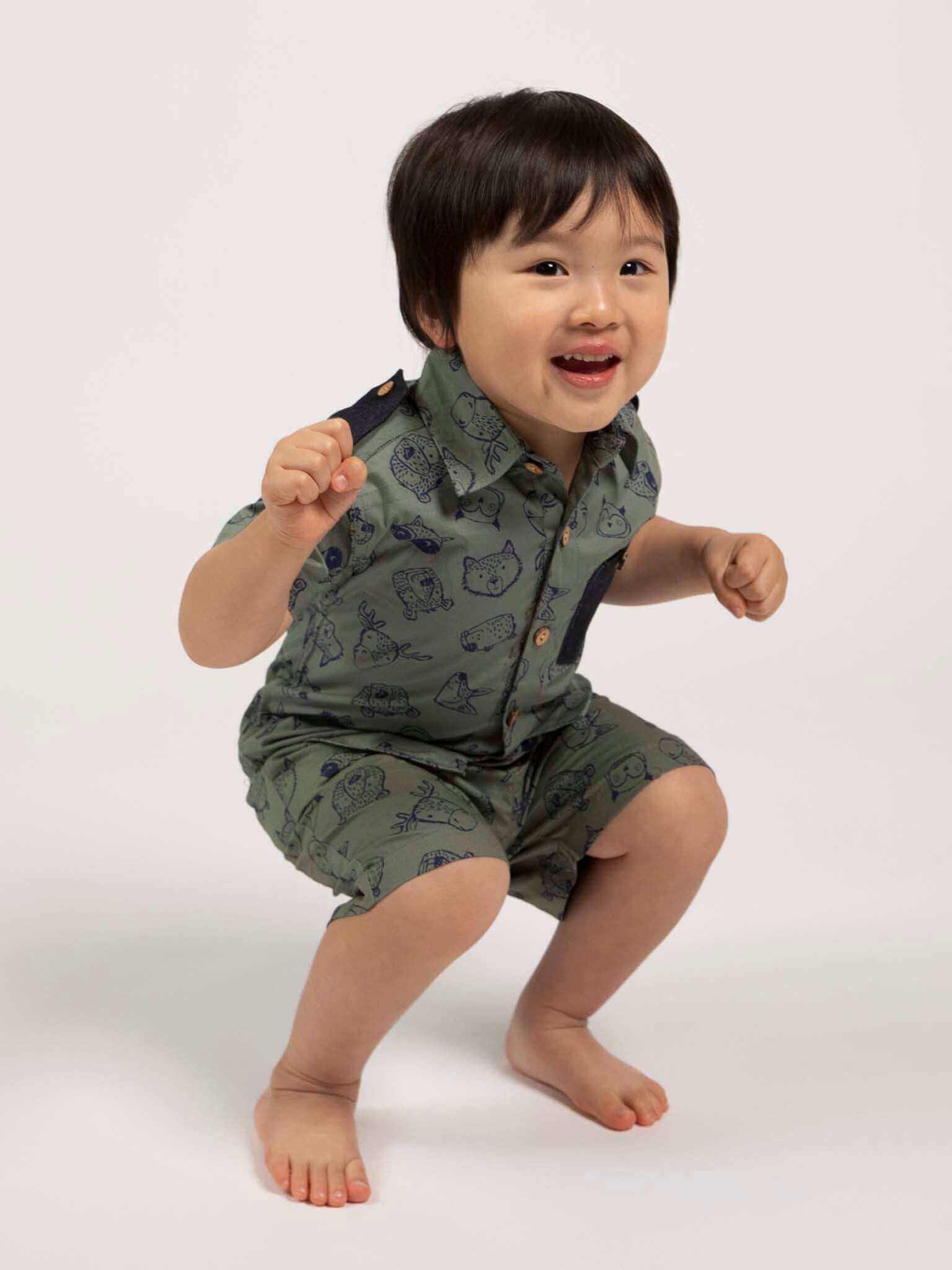 Child wearing a green outfit with animal designs on a white background