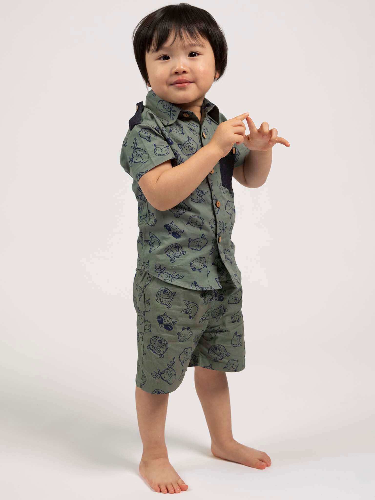 Child wearing a green patterned outfit on a white background