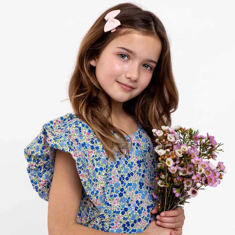 Girl wearing a bright Oobi dress, holding shopping bags, celebrating sale bargains.