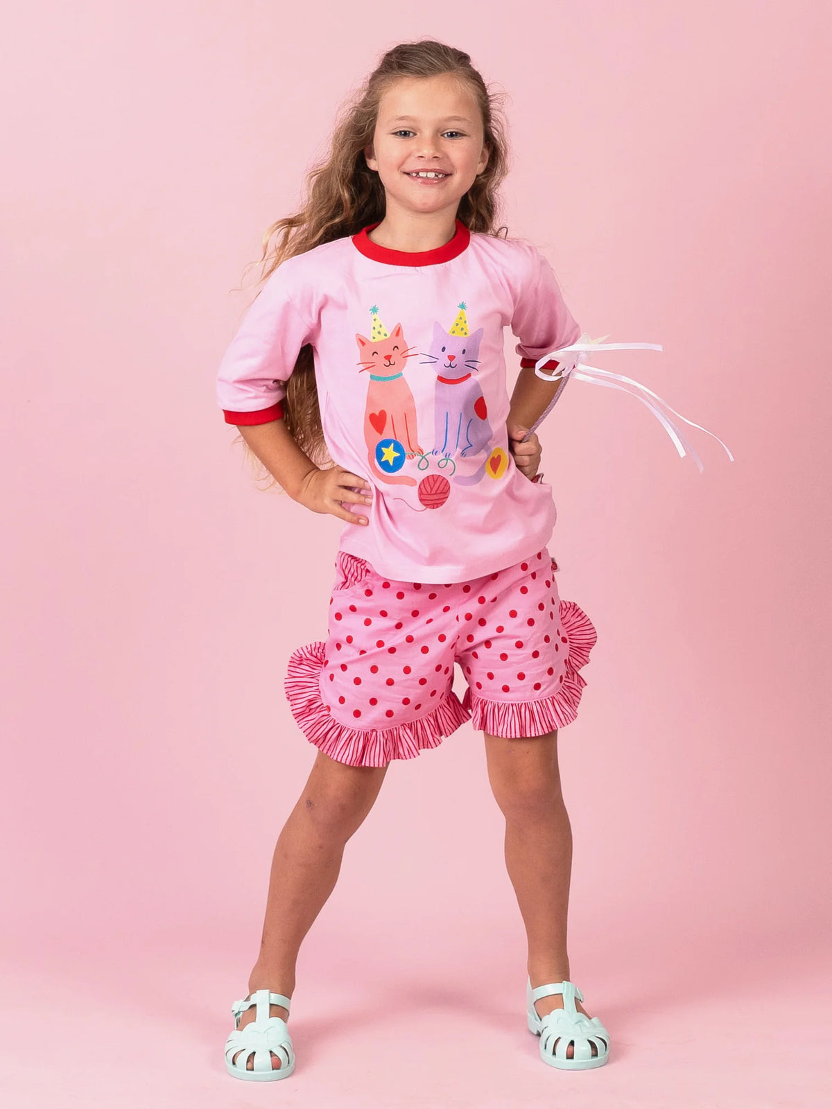 Girl in the pink Party Cats tee and Pink & Red Dots ruffle shorts, hands on hips