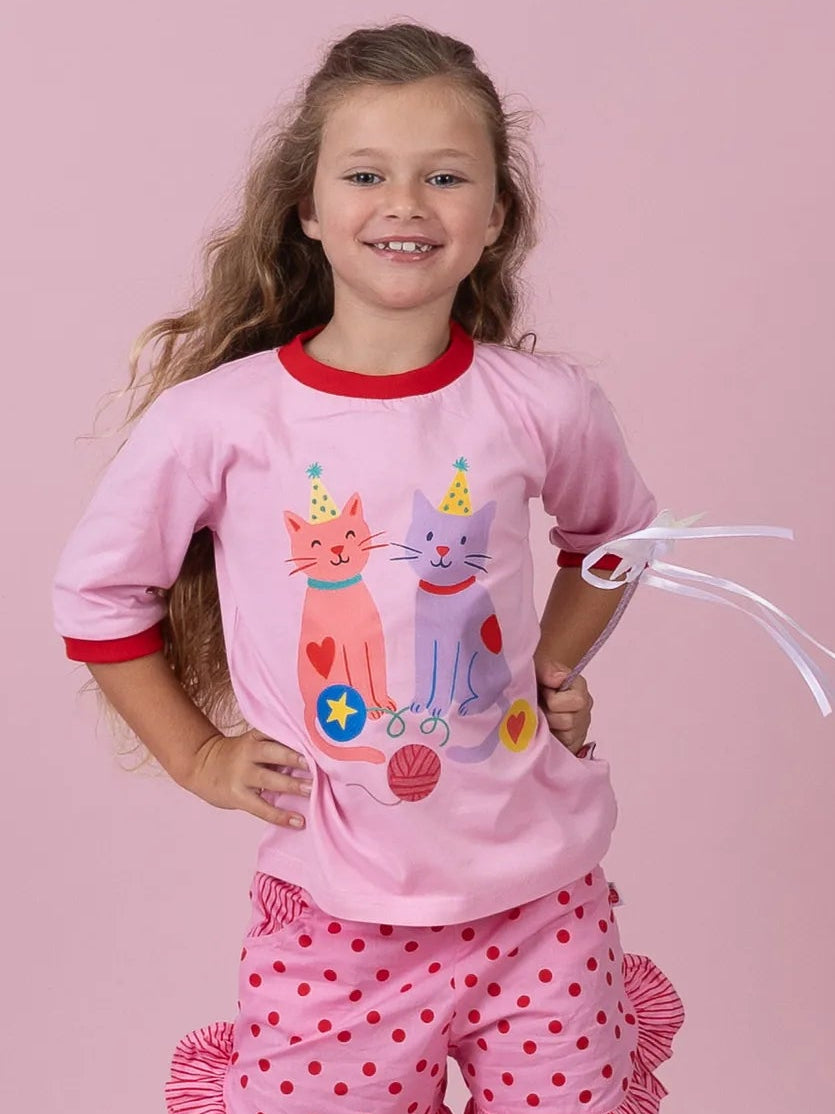 Girl in the pink Party Cats tee and Pink & Red Dots ruffle shorts, hands on hips