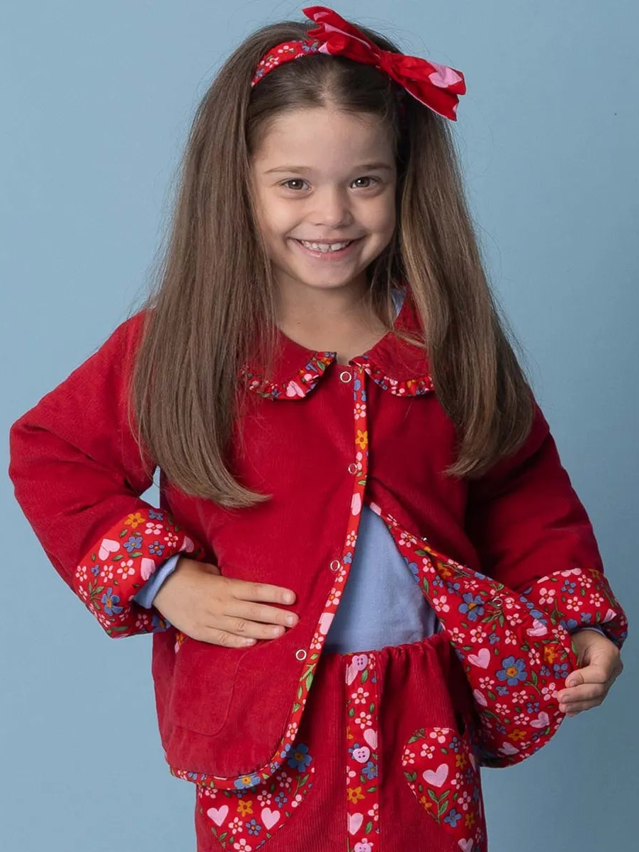 Young girl wearing a red floral jacket against a blue background
