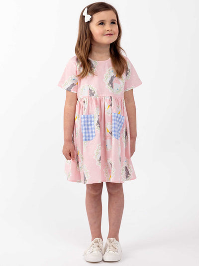 A cute little girl wearing a Pink Unicorn Magical Unicorn Megan Dress and white shoes.