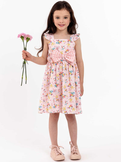 A little girl in a Vintage Pink Floral Mia Dress by Pink Flowers, holding a flower.