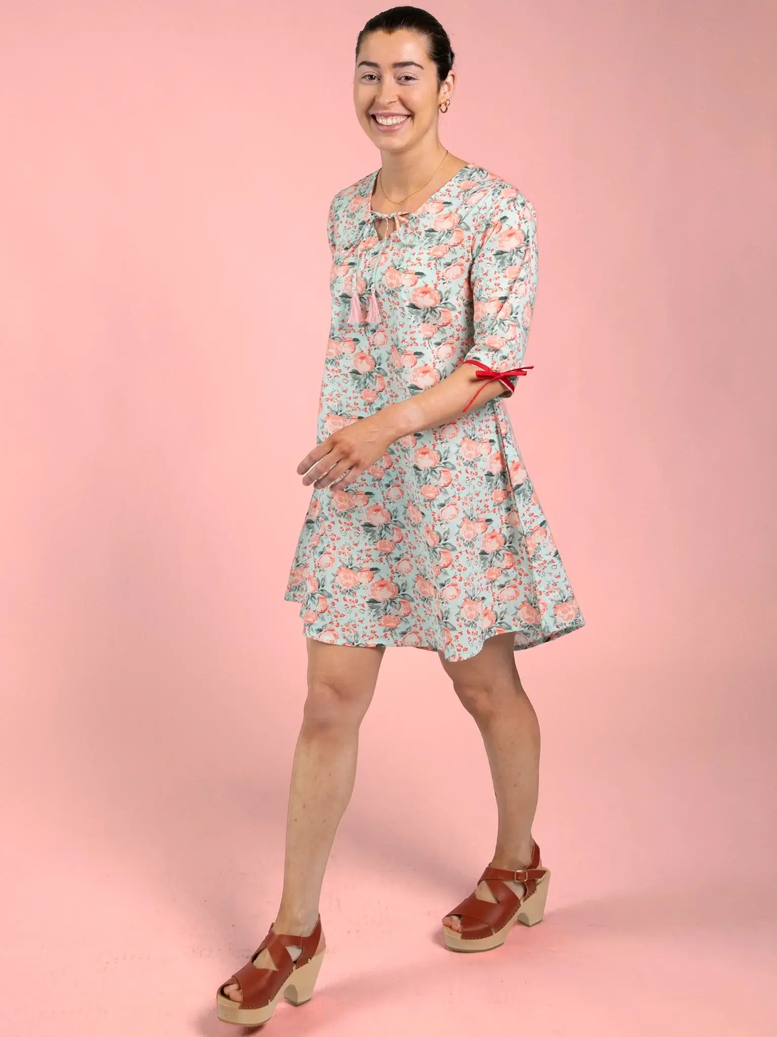 Woman wearing a floral dress on a pink background