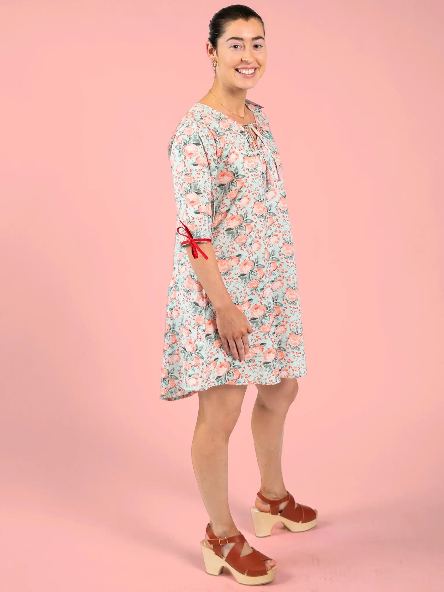 Woman wearing a floral dress with a pink background