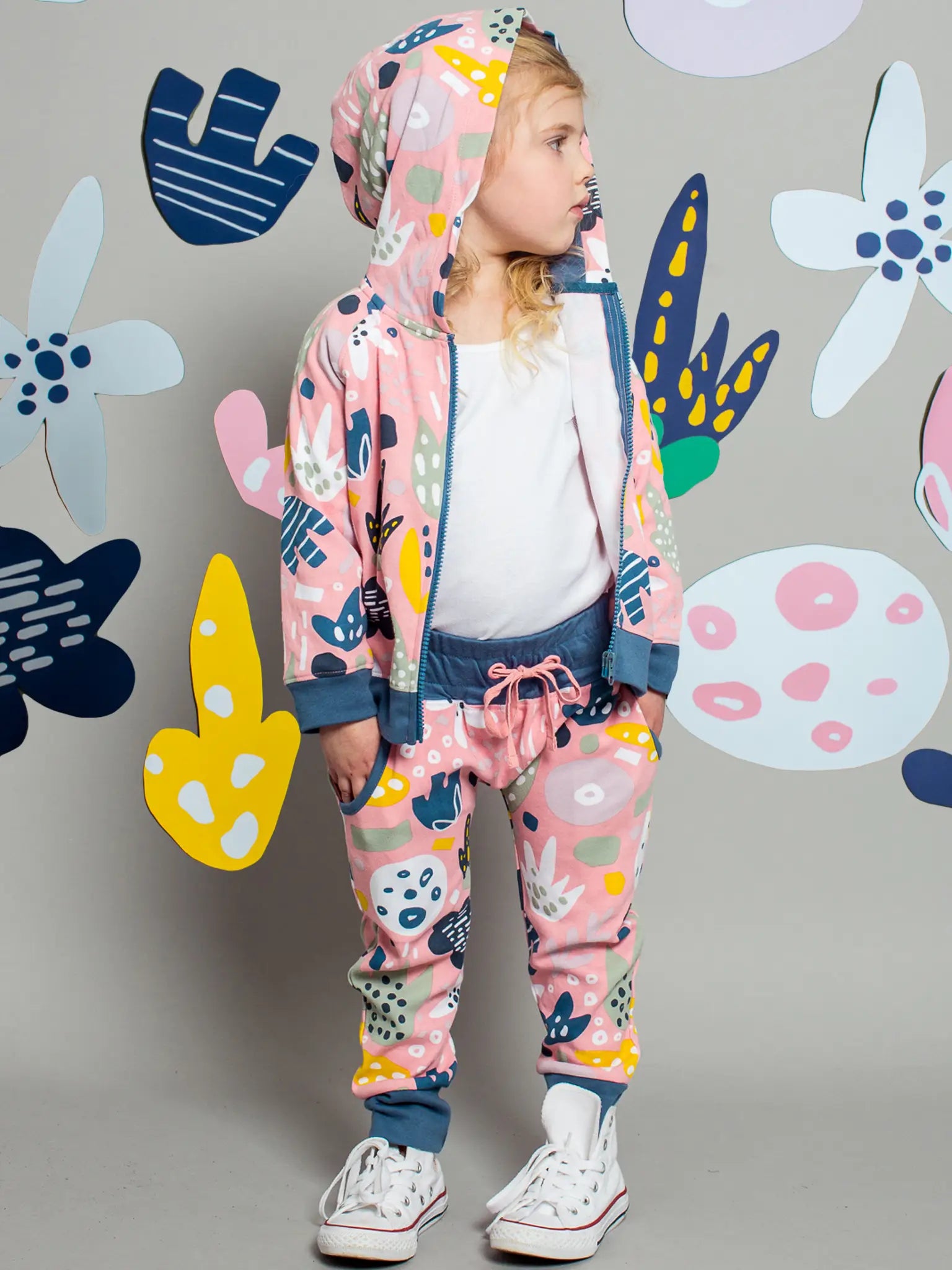 Child wearing a colorful outfit with abstract patterns on a gray background