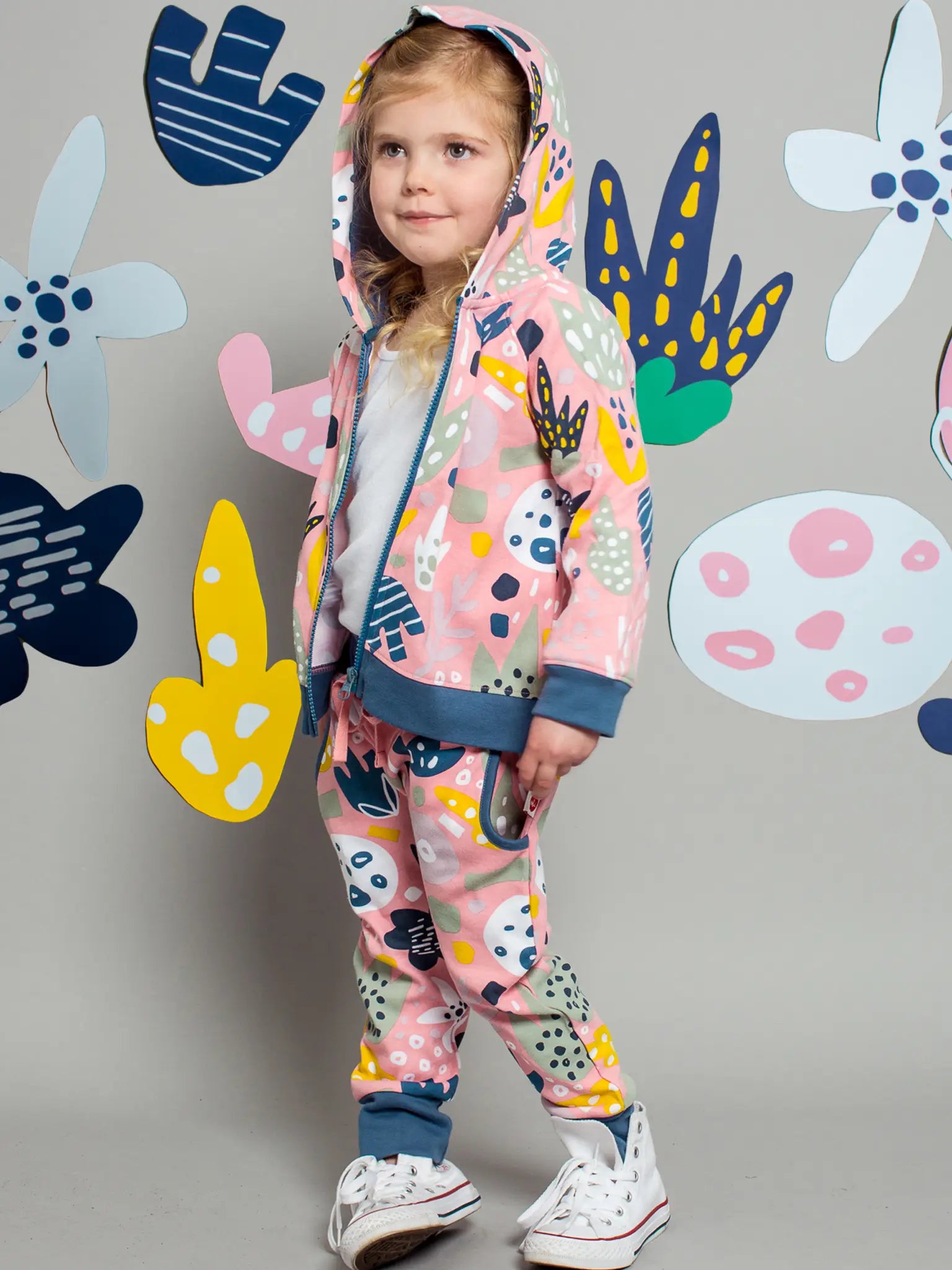 Child wearing a colorful outfit with abstract patterns against a decorative wall.