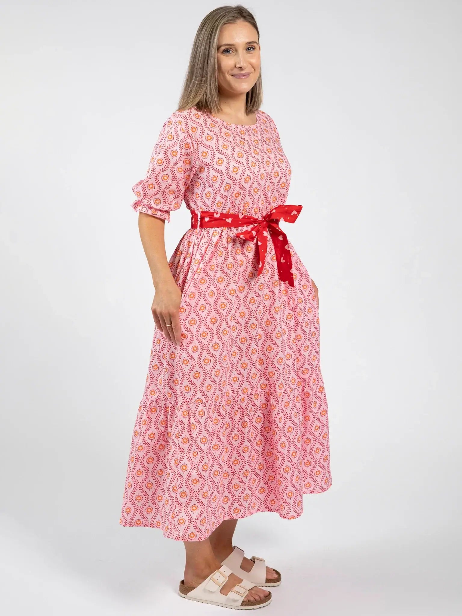 A woman in the Blue Stripe Women's Woodblock Maxi Dress [WH OK] stands on a white background, wearing sandals and smiling slightly.