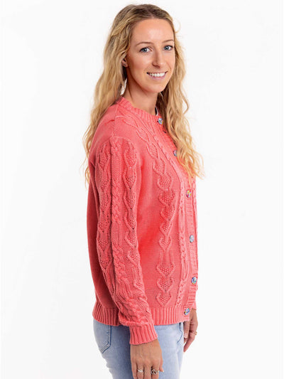 A woman wearing a Women's Willow Geranium Pink Cardigan by Knitwear with jeans.